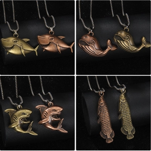 Vintage bronze animal necklaces featuring shark and whale pendants on black background