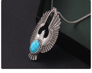 Détail du pendentif aigle vintage avec pierre turquoise bleue et textures de plumes