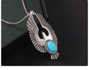 Vue macro d'un pendentif aigle vintage avec turquoise bleue sur une chaîne box en acier