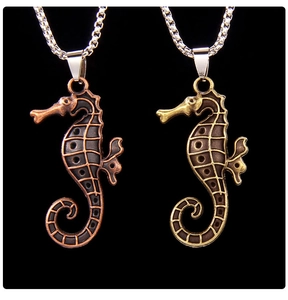 Detail of vintage seahorse necklaces in red and cyan bronze finishes with textured metal