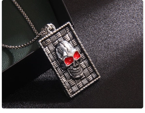 Close-up of punk style stainless steel dog tag necklace with red-eyed skull and metal chain