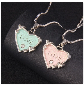 Detailansicht der Herzanhänger in Mint und Rosa mit LOVE-Gravur auf schwarzem Lederhintergrund