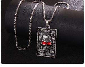Detail of silver skull dog tag necklace with red eyes on textured metal background