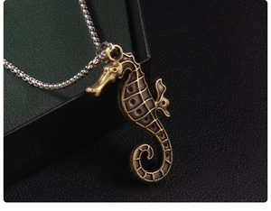 Close-up of vintage bronze seahorse pendant with detailed carving on a black background