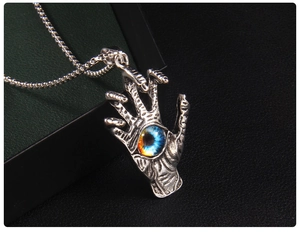 Macro detail of gothic skeleton hand pendant with blue evil eye on a box chain