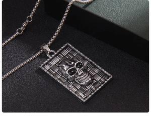 Detail of gothic skull dog tag pendant with red eyes on vintage steel chain
