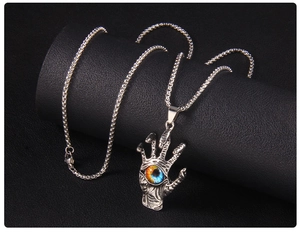 Detailed view of gothic skeletal hand pendant with realistic blue evil eye on box chain