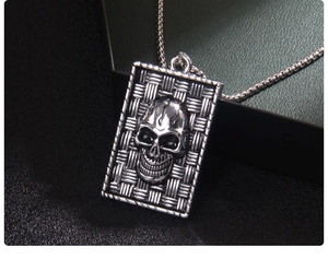 Detail of gothic skull relief on rectangular stainless steel pendant with woven texture