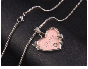 Makro-Detail einer silbernen Box-Halskette mit rosa glitzerndem Herzanhänger und LOVE-Gravur