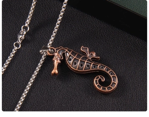Close-up of vintage seahorse pendant with textured bronze finish on box chain necklace