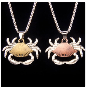 Detail view of retro crab pendants in antique gold and bronze finishes on silver chains