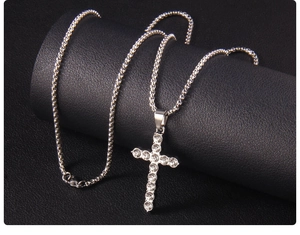 Macro detail of silver cross pendant with clear rhinestones on black leather stand