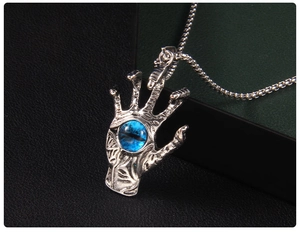 Macro detail of gothic skeletal hand pendant with blue evil eye on stainless steel chain