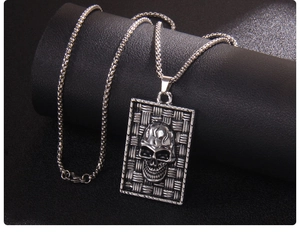 Detail of punk skull pendant necklace with mesh texture and silver box chain on black stand