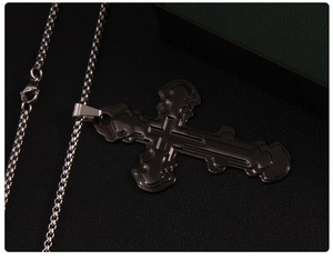 Macro shot of tiered black cross pendant with stainless steel round box chain on leather