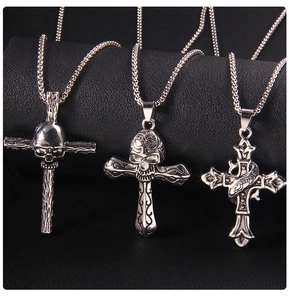 Gros plan de trois pendentifs croix gothiques vintage avec crânes sur support en cuir noir