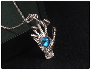 Macro shot of a gothic silver hand pendant with a deep blue evil eye on a box chain