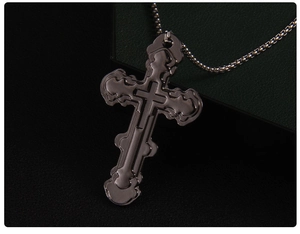Macro shot of dark stainless steel cross pendant with layered details on beaded chain