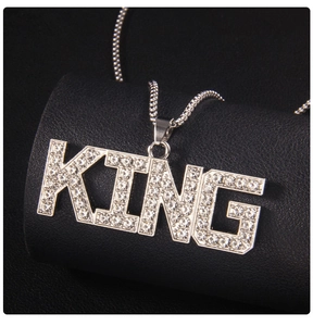 Macro shot of silver KING pendant with shimmering rhinestones on a black leather stand