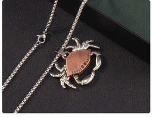 Detailed close-up of a vintage crab pendant with red copper shell and silver box chain