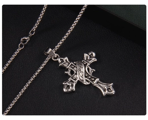 Détail du collier croix gothique en acier inoxydable avec gravures vintage sur fond noir