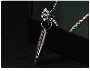 Macro detail of gunmetal bullet pendant with three clear zircons on square chain