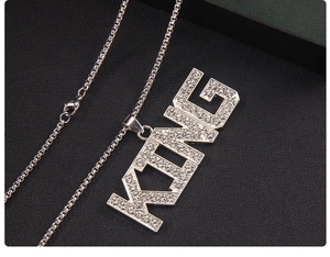 Close-up of iced out silver KING letter pendant with sparkling rhinestones on box chain