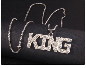 Macro view of silver KING letter pendant set with sparkling rhinestones and box chain