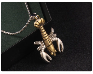Détail macro du pendentif homard bicolore avec finition bronze sur chaîne à billes