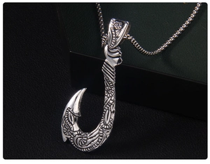 Gros plan d'un pendentif hameçon en argent vintage avec gravures tribales sur chaîne