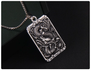 Macro detail of a vintage dragon totem relief pendant made of embossed stainless steel