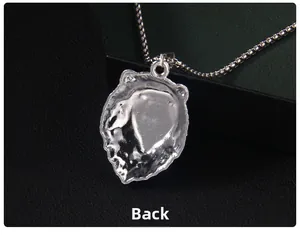 Détail macro montrant la vue arrière d'un pendentif tête de lion en acier et sa chaîne carrée
