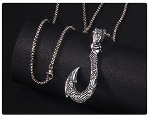 Vue détaillée d'un pendentif hameçon vintage argenté avec gravures tribales sur support
