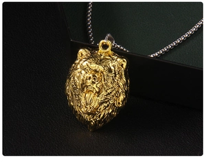 Vue macro d'un pendentif tête de lion dorée sur une chaîne à maillons fins argentés