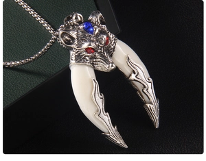 Detailed close-up of a vintage wolf head pendant with blue gemstone and resin fangs