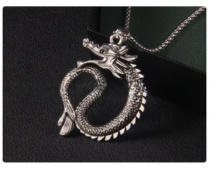 Dettaglio di un ciondolo a forma di drago in argento vintage con trame a scaglie e catena
