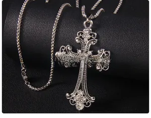 Macro del ciondolo a croce hip hop argento con strass scintillanti su sfondo in pelle