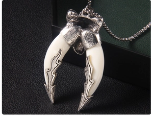 Detailed shot of double wolf fang pendant with silver flame patterns and beaded chain