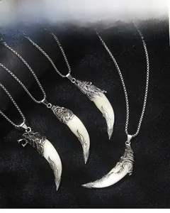 Détail des pendentifs dent de loup rétro avec motifs tête de loup gravés en argent