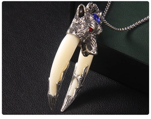 Detailed view of wolf head pendant with blue gemstone and dual resin fangs on black leather