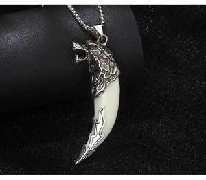 Détail macro du pendentif tête de loup argentée avec pointe ivoire et texture de flamme