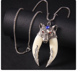 Macro detail of vintage wolf head pendant with red gemstone eyes and ivory tusks