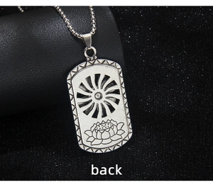 Macro detail of silver rectangular pendant showing lotus engraving and sunburst wheel