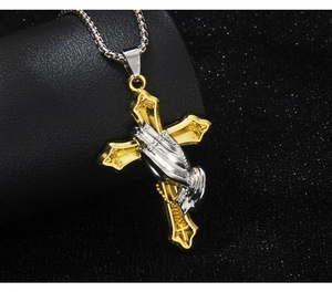 Detailed close-up of a silver prayer hand with a gold cross pendant on a square link chain