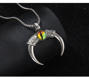 Macro shot of silver crescent devil eye pendant with intricate gothic engraving and bead chain