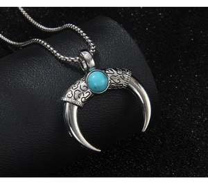 Macro shot of silver crescent horn pendant with blue stone on black leather