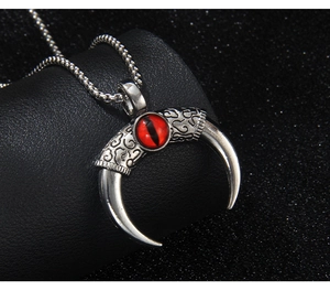 Macro detail of horn devil eye pendant with red stone and intricate scroll engravings