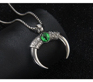 Detail of gothic crescent devil eye pendant with green stone and embossed patterns