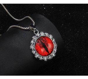 Macro shot of silver-tone evil eye necklace with red dragon eye and gothic pattern