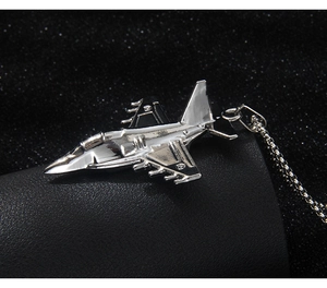 Close-up of a stainless steel fighter jet pendant with detailed wings on a black chain
